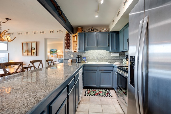 Your fully equipped kitchen features stainless steel appliances, granite countertops, and charming blue cabinetry—perfect for preparing meals at home during your stay.