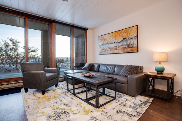 Unwind in your cozy living room with a stunning lake view framed by floor-to-ceiling windows. Sink into the plush leather sofa and let the natural light and peaceful scenery wrap you in comfort.