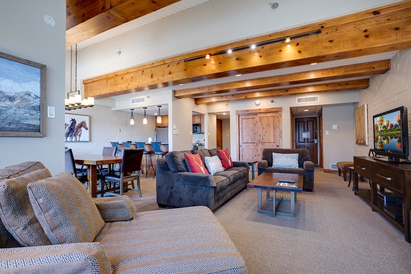 Unwind in your spacious open-concept living area, featuring soaring vaulted ceilings with rustic beams, plush seating, and mountain-inspired artwork that sets the tone for your alpine escape.