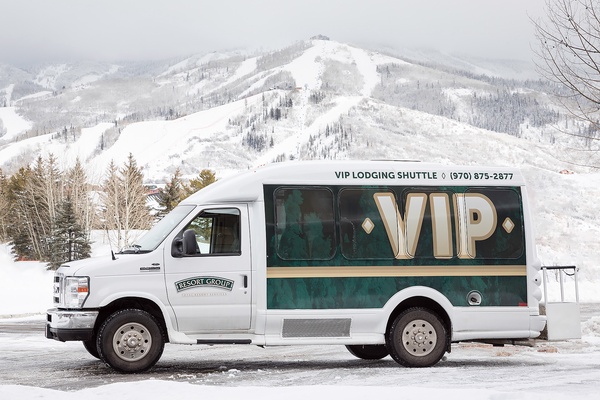 VIP shuttle service stands ready against snow-covered mountain slopes, offering convenient access to winter recreation and nearby ski areas.