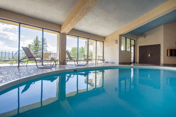 Slip into crystal-clear waters in your private indoor pool, where sunlight streams through floor-to-ceiling windows and comfortable loungers await you poolside—pure relaxation with views.