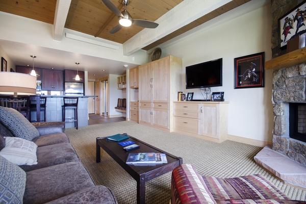 Settle into your spacious living area featuring vaulted wood ceilings, a cozy stone fireplace, and an open layout that flows seamlessly into the modern kitchen—perfect for unwinding after a day of adventure.