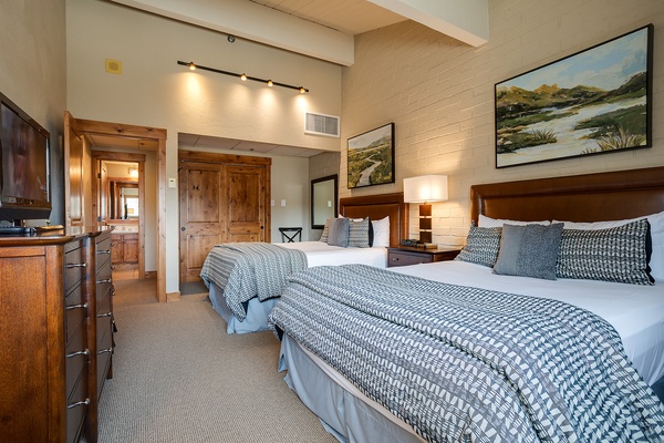 Sink into plush bedding and feel right at home in this bright, welcoming guest room featuring twin beds, elegant furnishings, charming artwork, and high ceilings that invite complete relaxation and restful sleep.