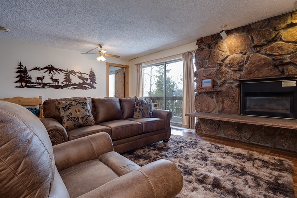 Settle into plush leather sofas beside a stunning stone fireplace, where rustic mountain charm meets modern comfort. Large windows frame scenic views while you relax in this cozy, inviting living room.