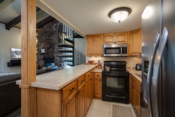 Your fully equipped kitchen features modern appliances, ample counter space, and warm wood cabinetry—perfect for preparing meals after a day of mountain adventures.