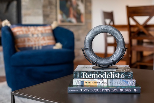 Sink into plush seating with a curated stack of design books at your fingertips, where stylish decor and cozy textures invite you to relax and unwind.