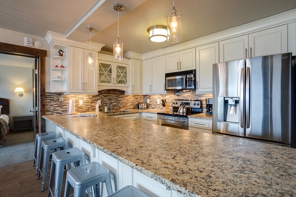 Spread out and savor your mornings in this bright, fully equipped kitchen featuring granite countertops, stainless steel appliances, and a spacious island with seating for casual dining.