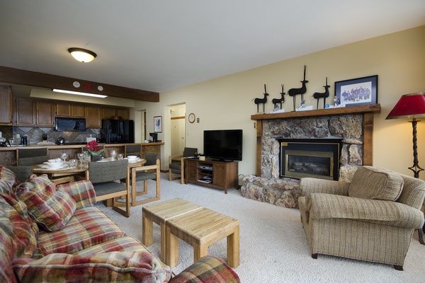 Settle into your cozy living space where a crackling stone fireplace and plush seating await. The open layout connects your kitchen and living areas for effortless gathering.