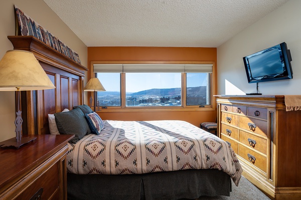 Wake up to sweeping mountain vistas from your comfortable bed, framed by warm wood furnishings and soft lighting that make every morning feel special.
