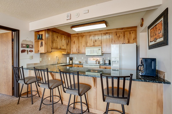 Your fully equipped kitchen with warm wood cabinetry and granite countertops invites you to whip up meals or enjoy morning coffee at the breakfast bar seating four.