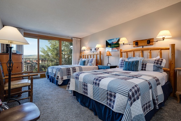 Settle into your cozy alpine retreat with rustic log headboards, plaid quilts, and scenic mountain views through your private balcony—perfect for peaceful mornings and starry evenings.