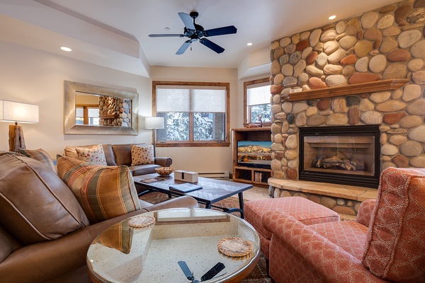 Sink into plush seating by your crackling stone fireplace as natural light pours through the windows. This cozy living space invites you to unwind after a day of adventure, with warm textures and a mountain retreat atmosphere.