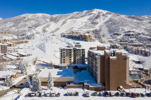 Ski resort nestled in snow-covered mountains with slopes and lifts visible. Winter destination surrounded by frosted trees and alpine lodges.