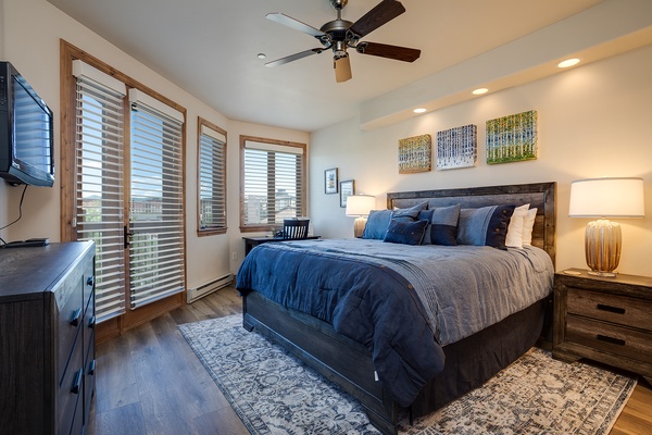 Sink into plush bedding and wake refreshed beneath the gentle hum of a ceiling fan. Large windows frame scenic views, while warm lighting sets a peaceful mood after your mountain adventures.