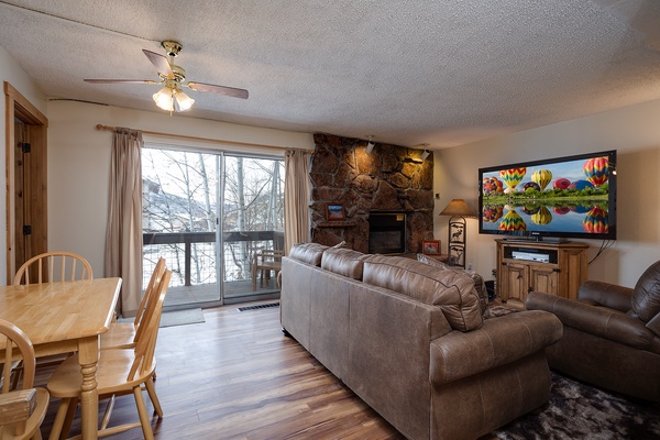 Unwind in your cozy living room with a stunning stone fireplace and large windows framing peaceful winter views. Settle into plush seating for movie nights or simply enjoy the serene ambiance.