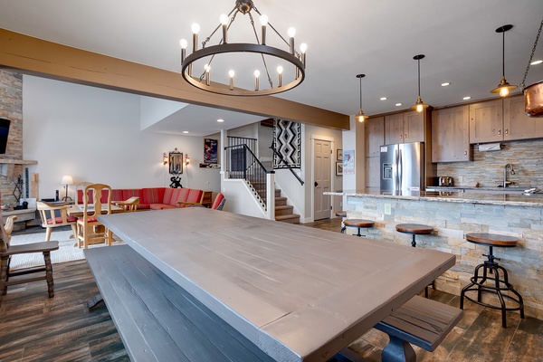 Step into your expansive open-concept retreat, where a dramatic circular chandelier illuminates rustic wood cabinetry, stone accents, and a generous island with bar seating—perfect for gathering with loved ones.