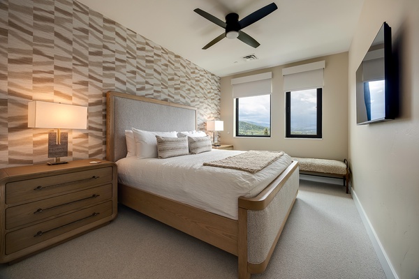 Drift off to peaceful sleep in this serene bedroom, complete with plush linens, a stunning textured accent wall, and windows framing sweeping mountain views that greet you each morning.