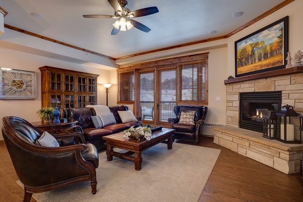 Unwind in your elegant living room with rich leather seating, a warming fireplace, and mountain views through classic wood-trimmed windows—your perfect retreat after a day of adventure.