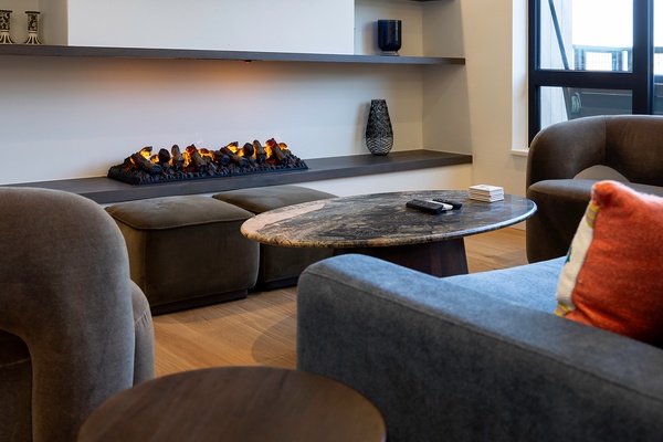 Unwind in your private living room where a modern fireplace casts a warm glow over plush seating and natural textures, inviting you to relax after a day of exploring.