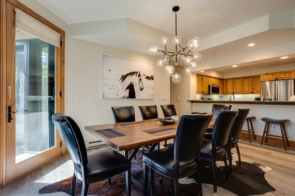 Gather around your beautiful dining table beneath elegant lighting, where meals become memorable moments with family and friends in this stylish open-concept space.