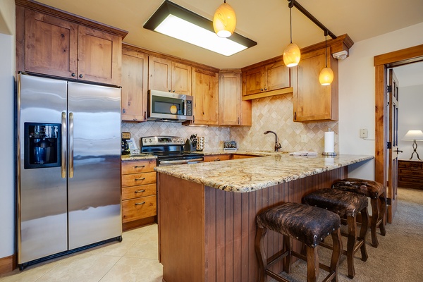Warm wood tones and granite counters create your inviting kitchen space. Gather around the island, whip up meals with modern appliances, and enjoy the cozy ambiance of pendant lighting overhead.