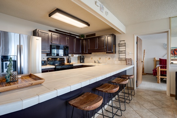 Gather your group around this spacious kitchen island, perfect for morning coffee or meal prep. Dark wood cabinets and modern appliances await your culinary adventures.