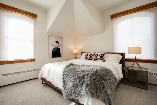 Sink into plush bedding and soft textures in your serene retreat. Natural light pours through arched windows, framing cozy modern touches that invite pure relaxation.