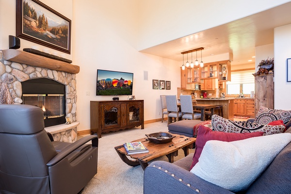 Sink into your cozy living space where a stone fireplace, comfortable seating, and open kitchen create the perfect mountain retreat for relaxing evenings together.
