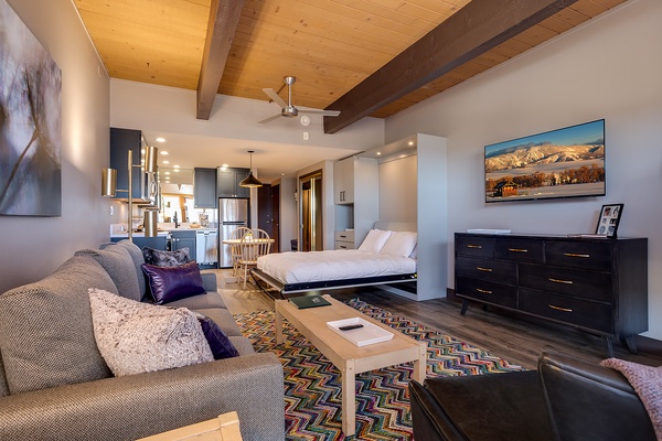 Your open-concept retreat features soaring wood-beamed ceilings, a plush living area, a cozy sleeping nook, and mountain views that remind you of the adventure waiting outside.