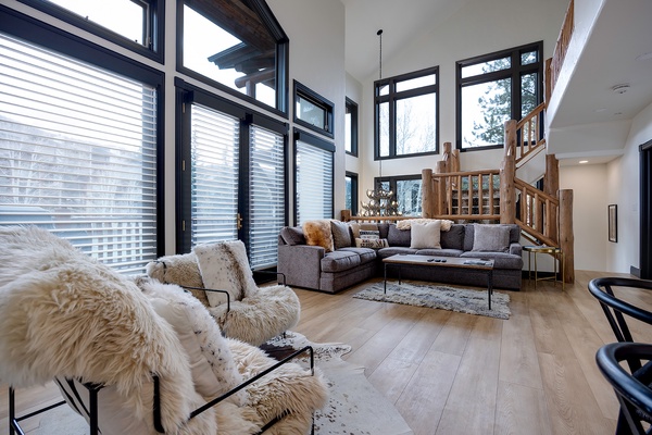 Sink into plush seating surrounded by soaring windows that frame snowy mountain views. Natural light fills your space, where cozy textures and modern mountain design create your perfect alpine retreat.