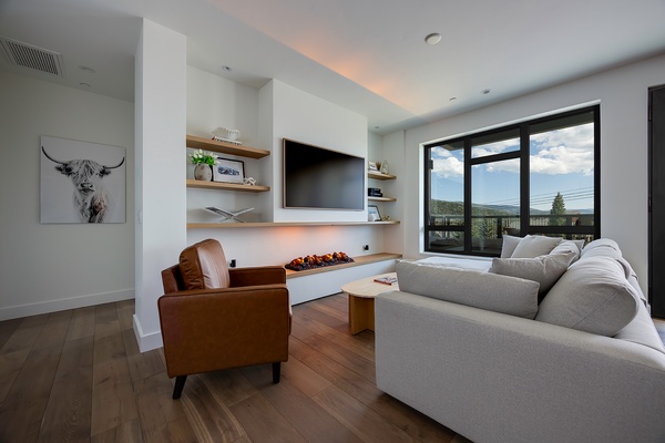 Unwind in this modern living room with a cozy fireplace and plush seating, where you can soak up mountain views through expansive windows.