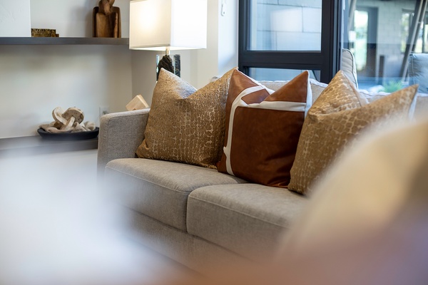Sink into plush cushions and unwind in your modern living space, where natural light streams through sleek black-framed windows and thoughtful design meets everyday comfort.