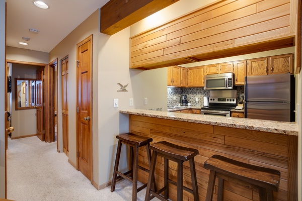 Gather at the breakfast bar in your fully equipped kitchen, where rich wood tones and granite counters create a warm mountain retreat feel. Everything you need for home-cooked meals is right at your fingertips.