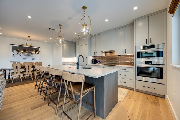 Step into your modern chef's kitchen, fully equipped with sleek stainless appliances and an elegant island perfect for morning coffee or gathering with friends over a home-cooked meal.