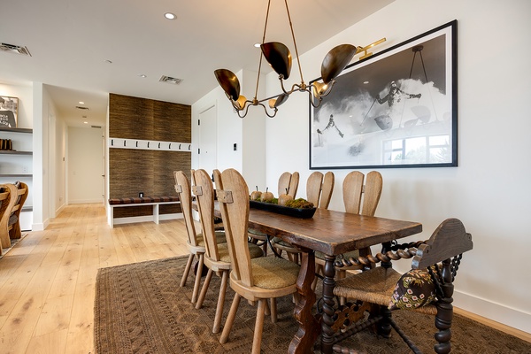 Your dining space awaits with a striking handcrafted table set beneath a sculptural chandelier. Rich wooden floors and artisan details create an inviting atmosphere for memorable meals together.