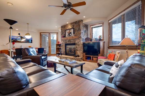 Sink into plush leather seating by the stone fireplace. Your mountain retreat blends warmth, natural light, and plenty of room to unwind after a day of adventure.