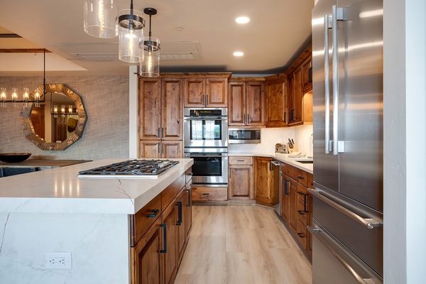 Picture yourself preparing meals in this spacious kitchen, where warm wood cabinetry meets sleek stainless steel appliances and elegant marble countertops invite culinary creativity.