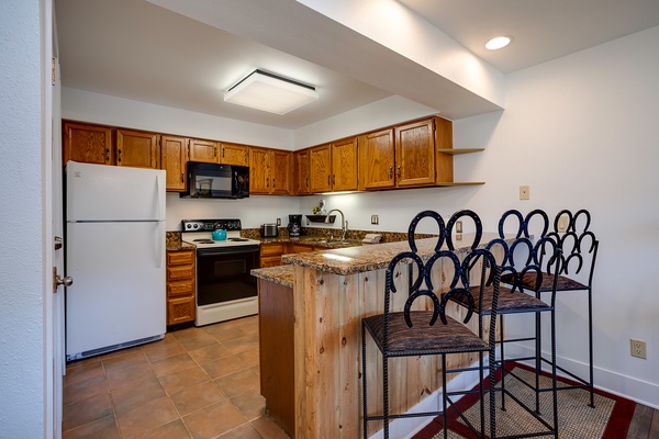 Your fully-equipped kitchen features warm wood cabinetry, granite countertops, and a charming breakfast bar with seating—perfect for preparing meals and gathering with family.