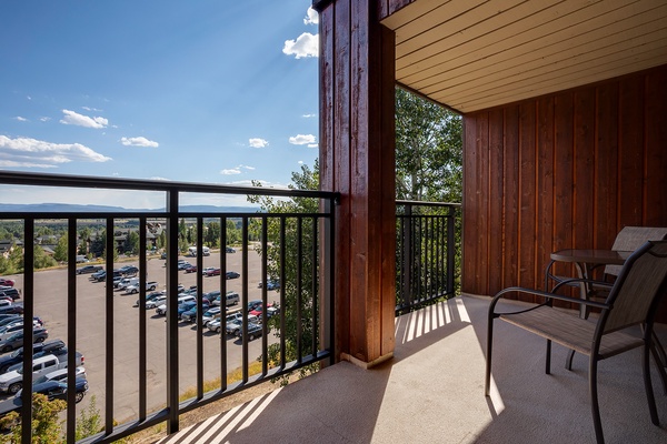 A balcony offering mountain vistas and open skies, with seating for relaxation. The property is situated in a neighborhood area with parking facilities nearby.