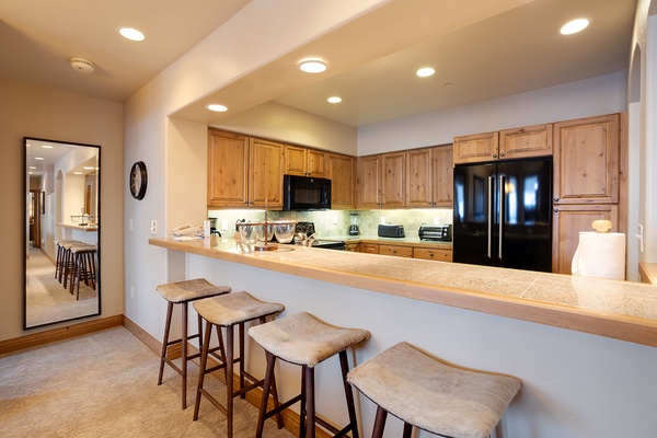 Gather around this spacious kitchen with warm wood cabinetry and a generous breakfast bar where your mornings unfold with coffee and conversation.