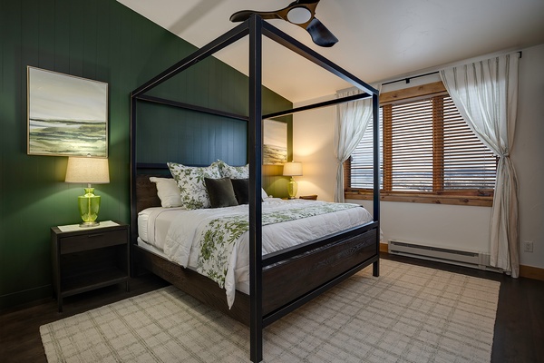 Drift off in this elegant canopy bed with botanical linens, surrounded by calming green walls and soft lamplight that create your perfect retreat.