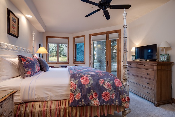 Wake up in this inviting bedroom with views of evergreen trees and snowy slopes just beyond your window. The elegant four-poster bed, warm wood furnishings, and cozy ceiling fan create your perfect mountain retreat.