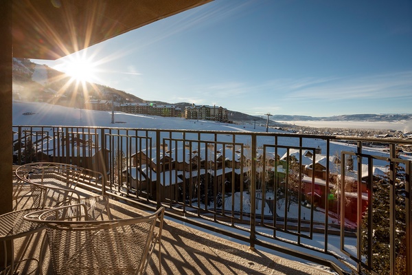A bright winter morning greets the property, with snow-covered slopes rising above the valley below and sunshine streaming across nearby buildings and rooftops.
