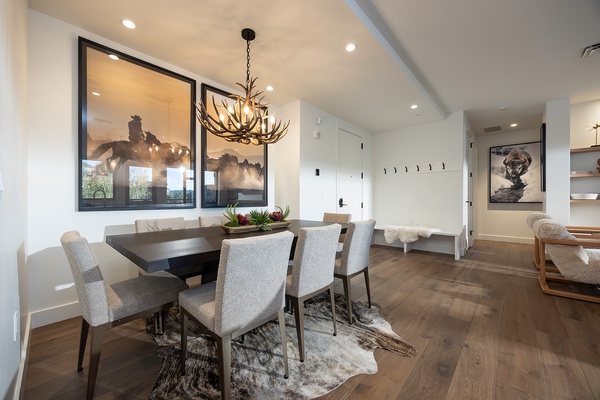 Gather around the stunning dark wood table under a dramatic antler chandelier, where memorable meals and conversations await in your elegant dining space.