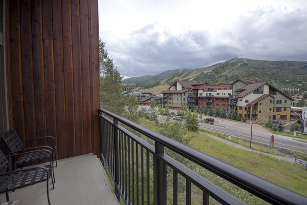 A mountain resort town with forested slopes and multi-story lodges nestled at the base of rolling peaks.