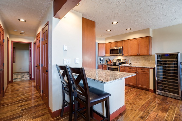 Your fully-equipped kitchen features warm wood cabinetry, granite countertops, stainless appliances, and a breakfast bar perfect for morning coffee or casual meals together.