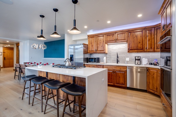 Gather around the spacious island in your gourmet kitchen, featuring warm wood cabinetry, sleek stainless appliances, and a gas cooktop—perfect for preparing meals together and creating lasting memories.
