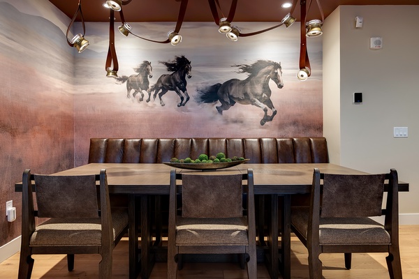 Your private dining space invites unforgettable meals beneath dramatic lighting and stunning artwork. Settle into the tufted leather banquette and savor every moment around this handsome table designed for togetherness.
