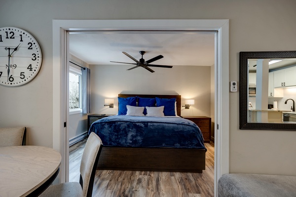 Step into your serene bedroom retreat with plush bedding, warm lighting, and a ceiling fan to keep you cool—your restful night awaits in this inviting space.