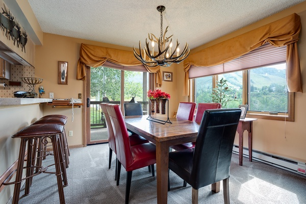 Gather around this handsome dining table beneath a striking antler chandelier, with mountain views framing your meals and sliding doors opening to the fresh air beyond.